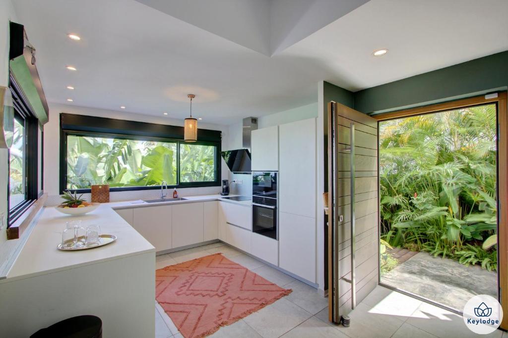 a kitchen with white cabinets and a large window at Villa Paloma 4 étoiles avec Piscine et Vue exceptionnelle sur l&#39;ocean à Saint-Leu in Saint-Leu