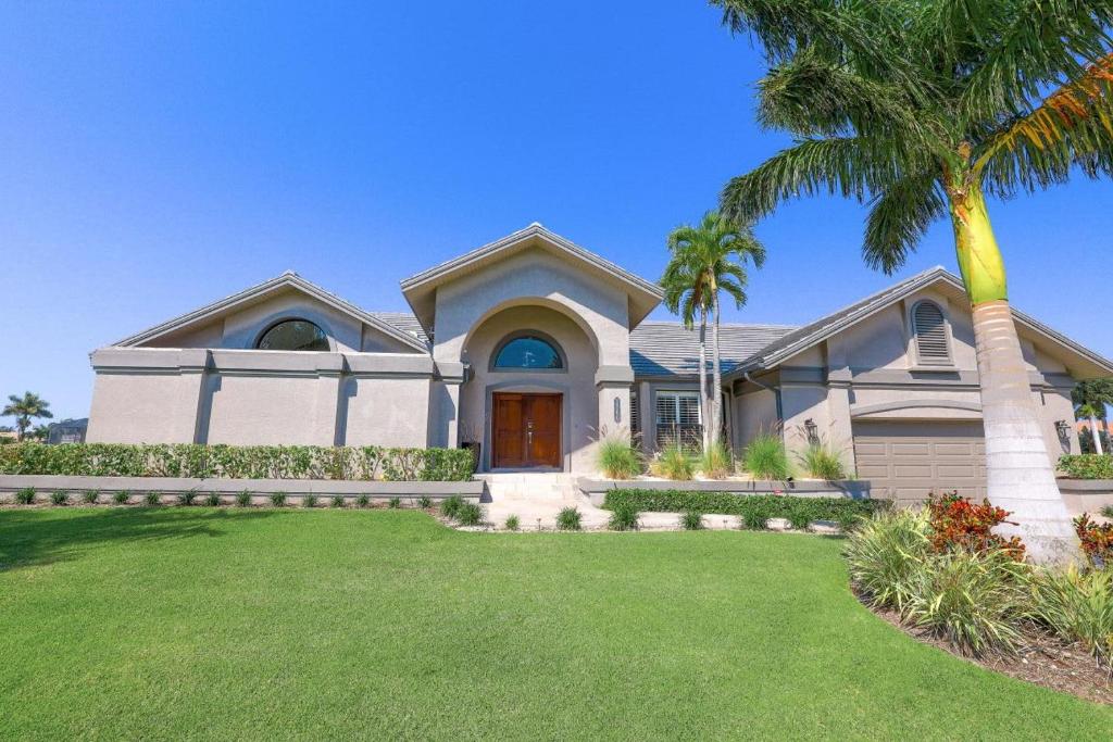 a house with a palm tree in front of it at Stunning home with pool, dock and direct gulf access in Marco Island