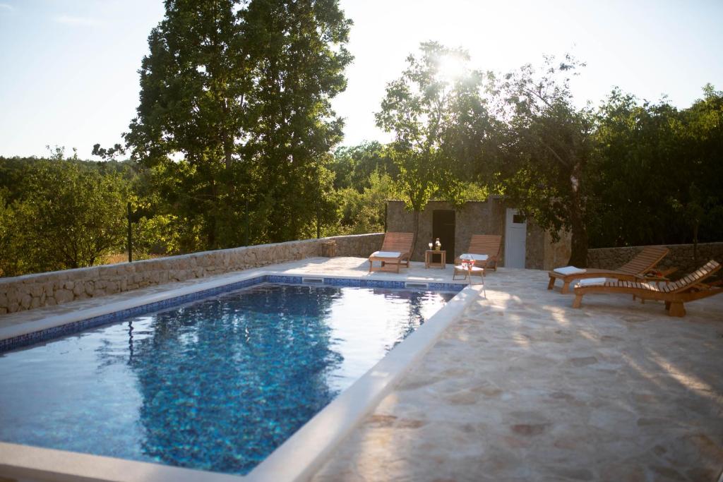 a swimming pool with two chairs and a table at Holiday Home Pearl in Stone in Imotski