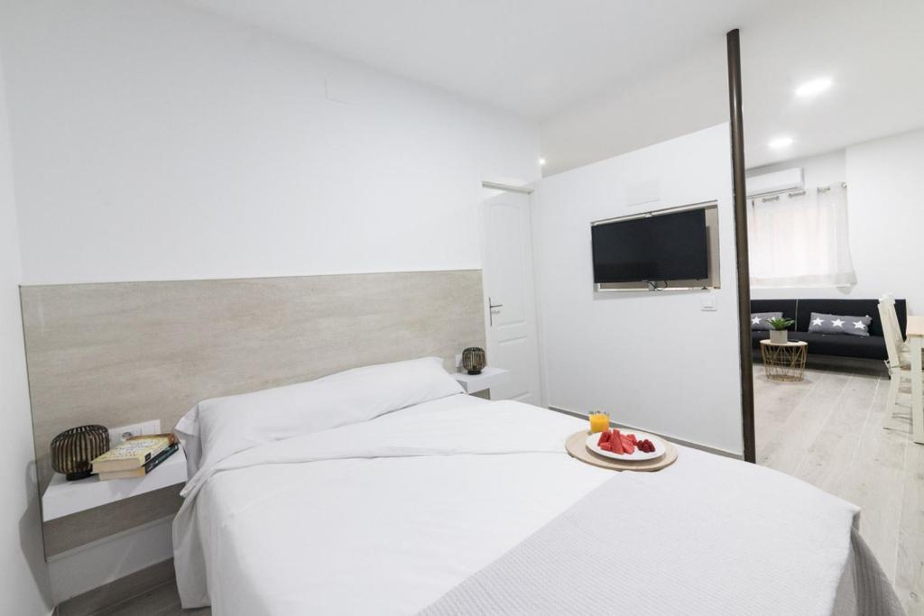 ein weißes Schlafzimmer mit einem Bett und einem Tisch mit einem Obstteller in der Unterkunft Moonkey - Apartamento Amaralba B in Alicante