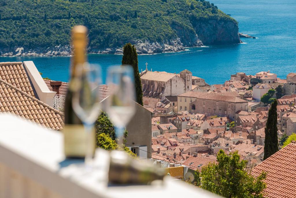 a view of a city with wine glasses on a ledge at Guest house AllineedDubrovnik Choose between Double room or penthouse or studio apartments FREE PARKING in Dubrovnik
