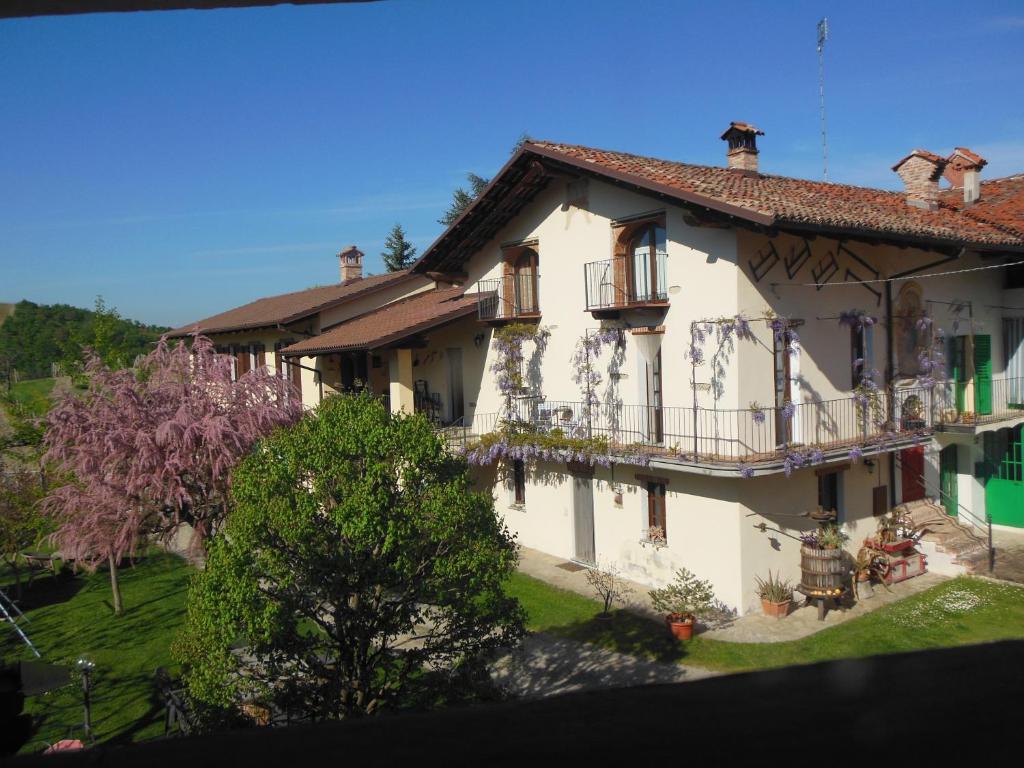 a large white building with balconies and trees at Agriturismo Affittacamere Barbarossa in Dogliani