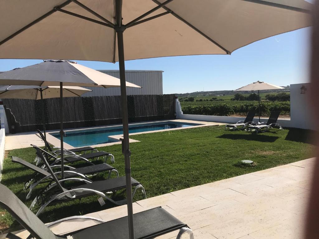 a group of chairs and umbrellas next to a pool at Herdade das Castas Nobres in Redondo