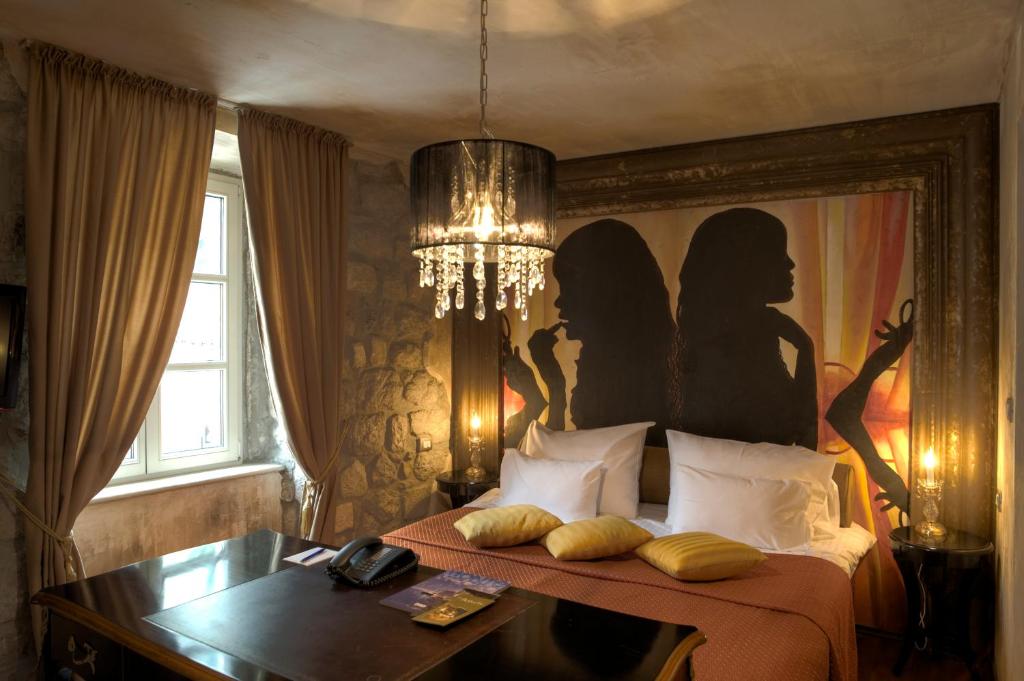 a room with a bed, a lamp and a painting on the wall at Boutique Hotel Astoria in Kotor