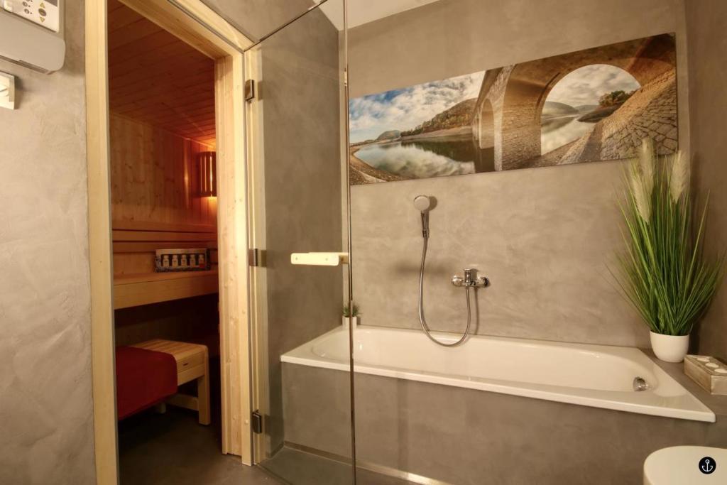 a bathroom with a bath tub with a painting on the wall at Haus Luce - Sonnenweg 13 in Heringhausen