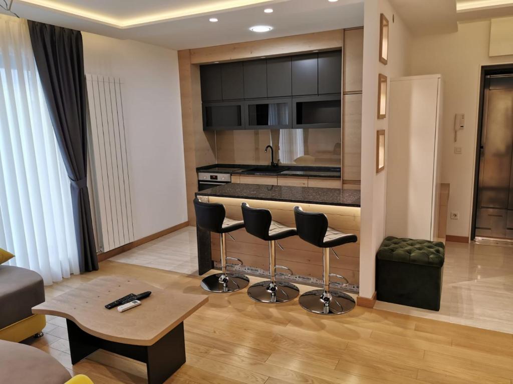 uma sala de estar com uma cozinha com bancos de bar em Captain's Apartment em Karaburma