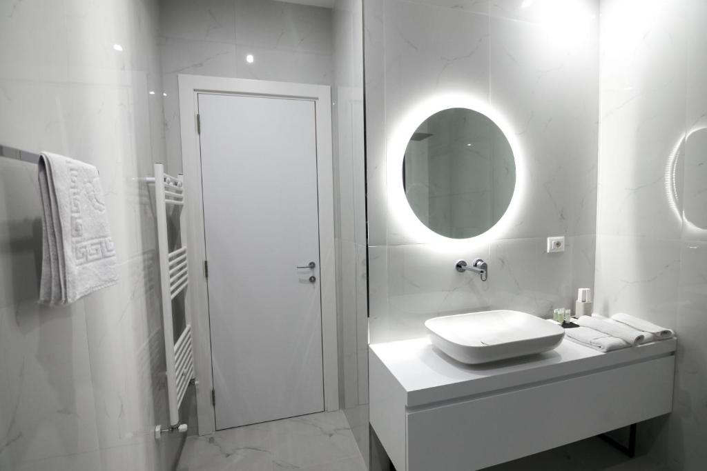 a white bathroom with a sink and a mirror at N Hotel BY NOSHI in Rinas