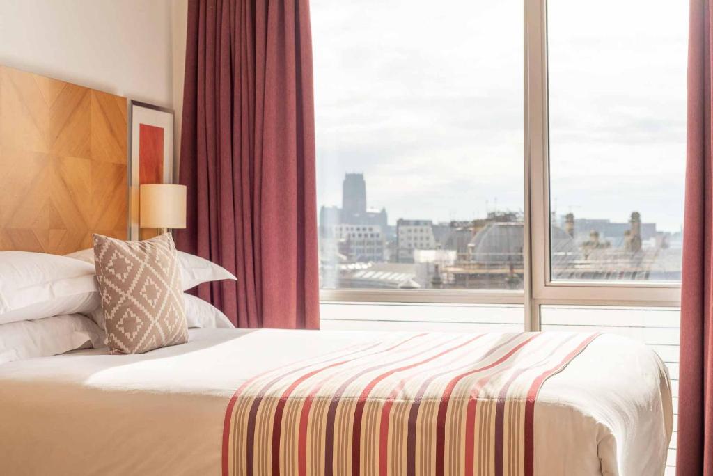 - une chambre avec un lit et une grande fenêtre dans l'établissement PREMIER SUITES Liverpool, à Liverpool