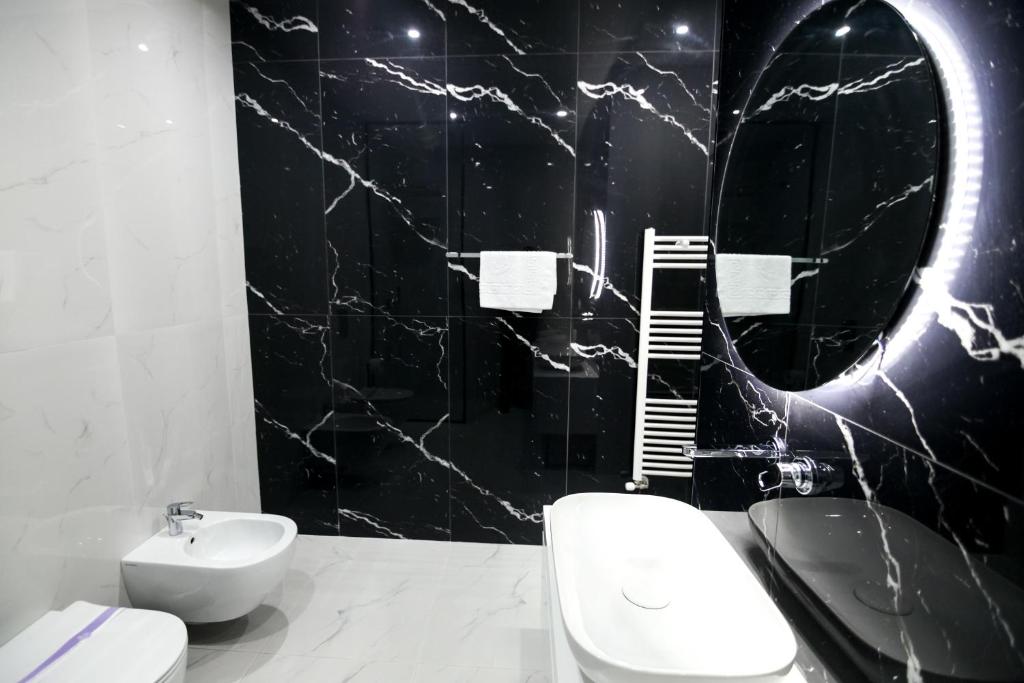 a bathroom with a white toilet and a black wall at N Hotel BY NOSHI in Rinas