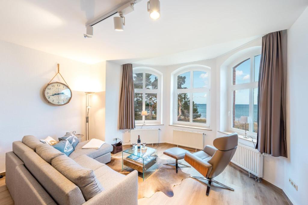 a living room with a couch and chairs and windows at Villa Glückspilz by Schewe in Binz