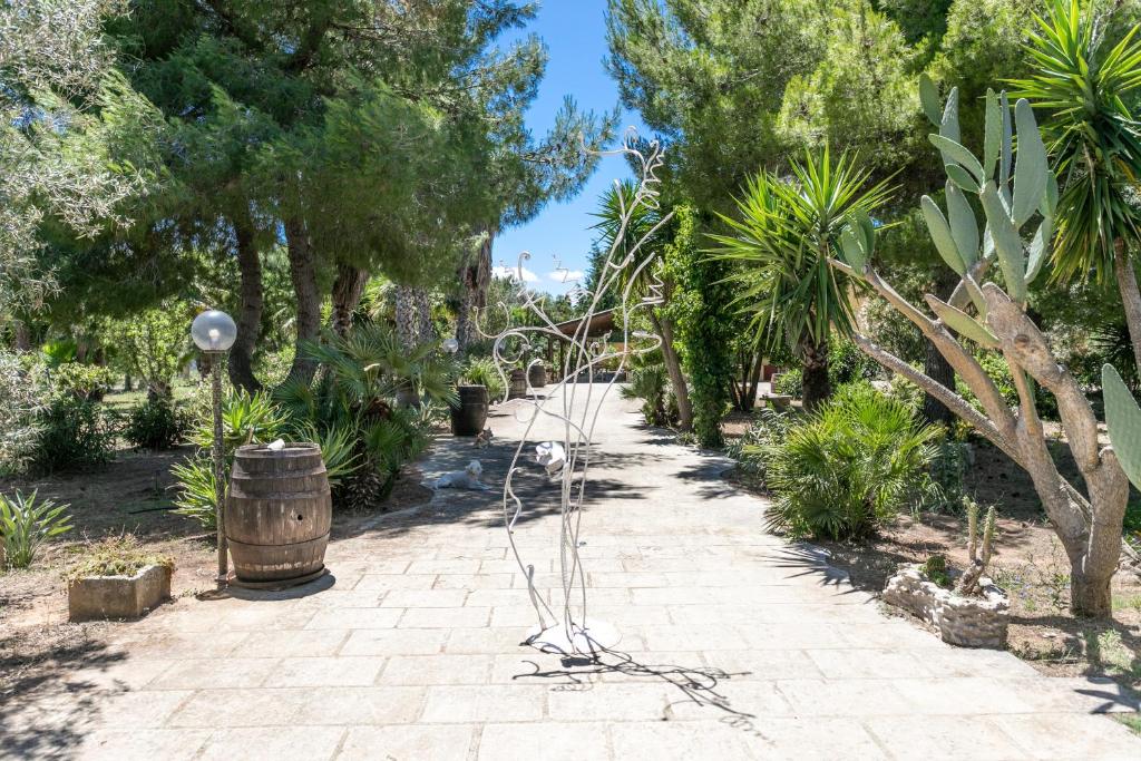 einen Garten mit Bäumen, einem Fass und einer Skulptur in der Unterkunft Le Palmentelle - Masseria con piscina in San Cesario di Lecce
