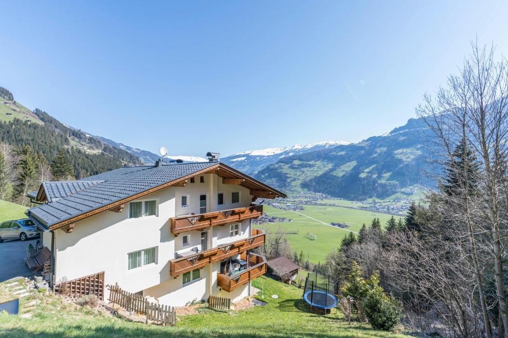 a house on a hill with mountains in the background at Ferienwohnung Helena in Schwendau