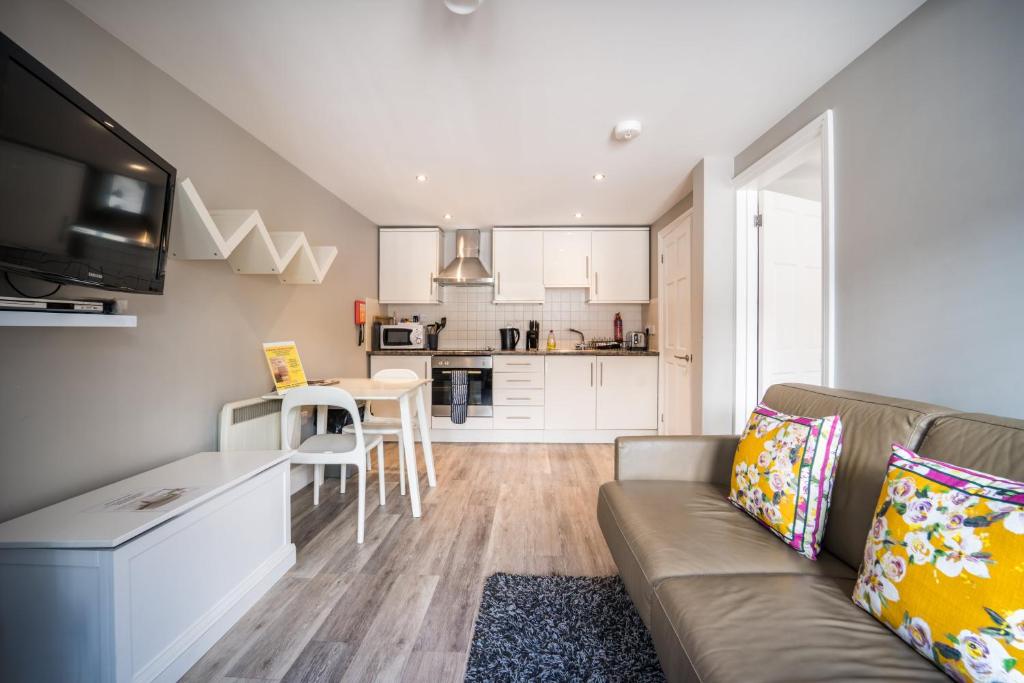 a living room with a couch and a kitchen at Trinity Mews in Torquay