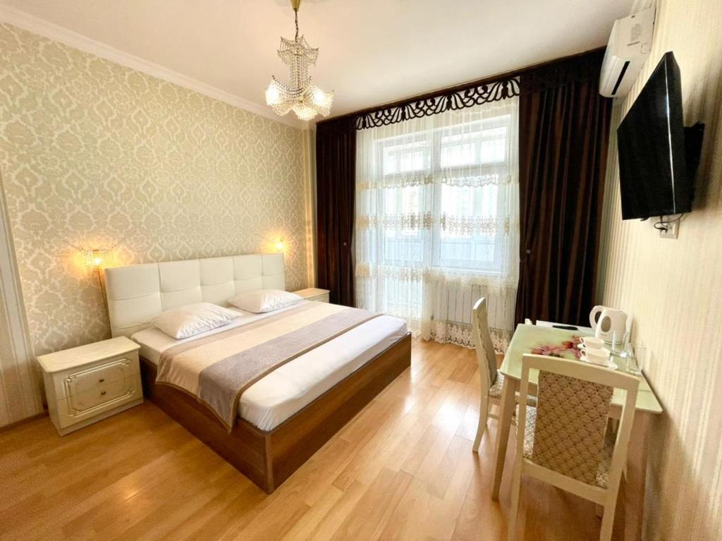 sypialnia z łóżkiem, stołem i oknem w obiekcie Mini-Hotel Sultan w mieście Astana