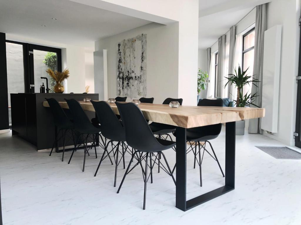 une salle à manger avec une table en bois et des chaises noires dans l'établissement NYAMAN, à Ostende