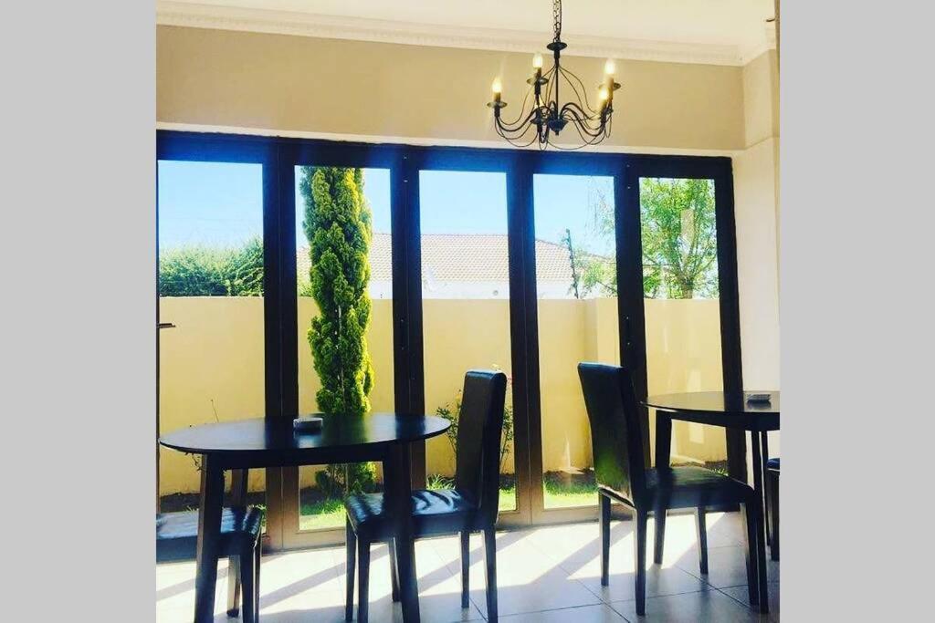 a dining room with a table and chairs and windows at Olive Exclusive in Gaborone