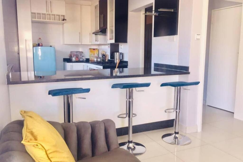 a kitchen with a couch and a counter with stools at Olive Exclusive in Gaborone