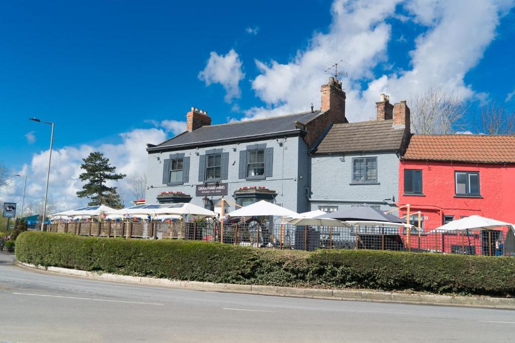 ein Gebäude mit Tischen und Sonnenschirmen davor in der Unterkunft Grantham Arms in Boroughbridge