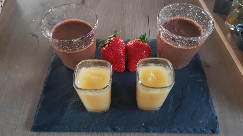 three glasses of orange juice and strawberries on a blue plate at gite A L' ÉVIDENCE in Mornas