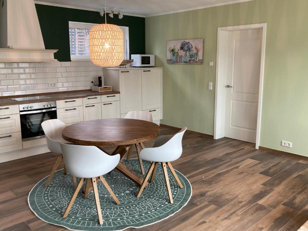 a kitchen with a wooden table and white chairs at Timeout Lodges - Luxus für Zwei in Dudeldorf