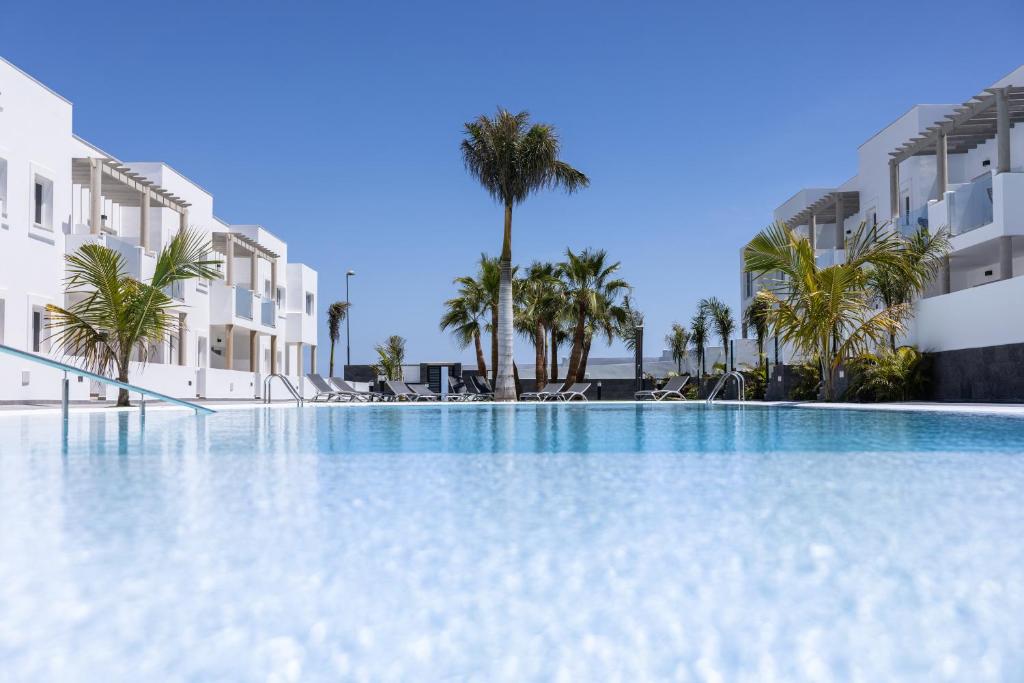 uma grande piscina com palmeiras e edifícios em Island Home Fuerteventura em Corralejo