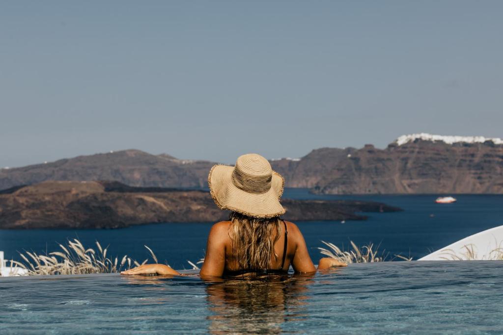 a woman in a hat sitting in the water at Akrorama private villas and suites in Akrotiri