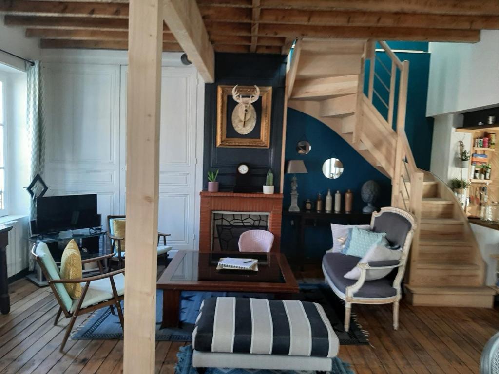 Una sala de estar con una escalera y una mesa y sillas. en La maison de la baie, wifi, terrasse, 200m du port, en Saint-Valery-sur-Somme