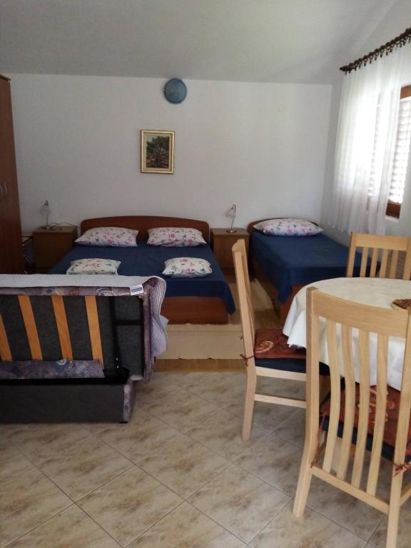 a bedroom with two beds and a table and chairs at Jagoda Apartments in Zaostrog