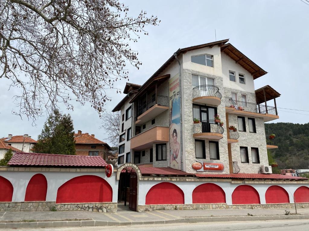 a building with red and white doors and a building at Hotel Chinara in Ognyanovo