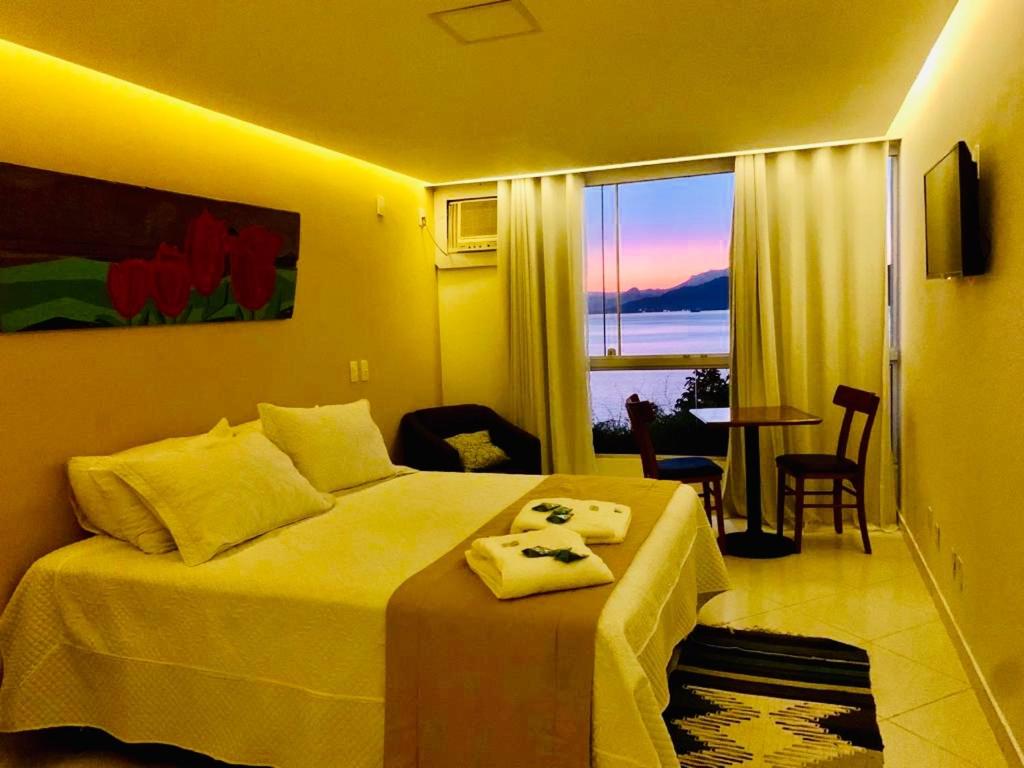 a hotel room with a bed and a view of the ocean at Pousada Costão do Sol in Angra dos Reis