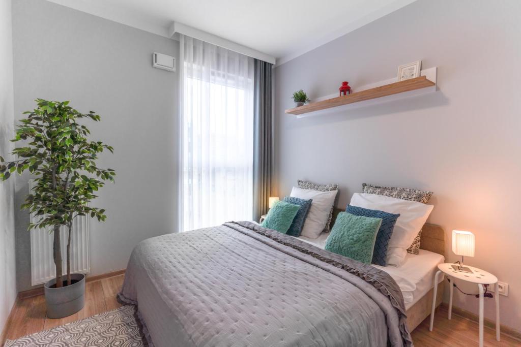 a bedroom with a bed and a potted plant at Apartamenty Homely Place Centrum - Stary Rynek - Parking in Poznań