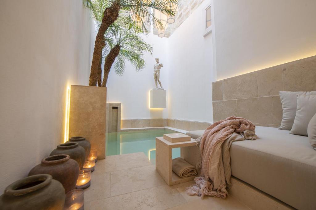 - une chambre avec un lit, une table et un palmier dans l'établissement Palazzo Lecce - Epoca Collection, à Lecce
