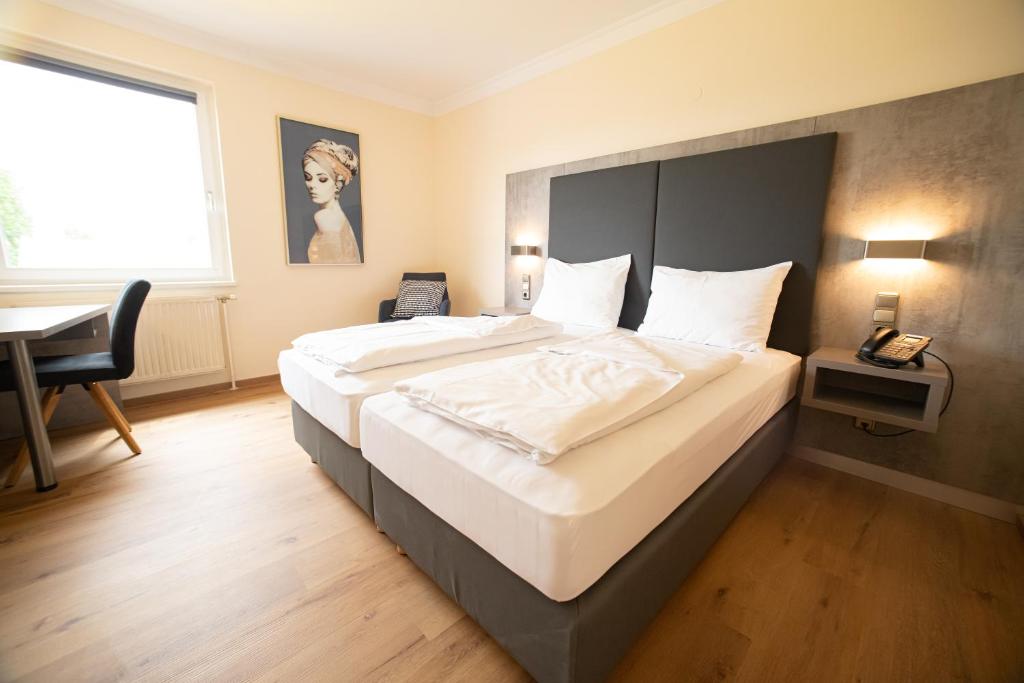 a bedroom with a large white bed with a desk at Das Reinisch Just Rooms in Schwechat