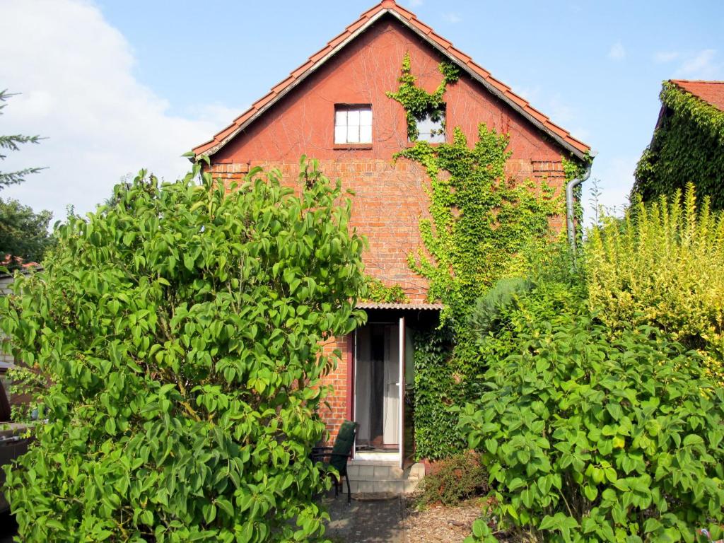 uma antiga casa de tijolos com uma janela e arbustos em Holiday Home Jana by Interhome em Buchholz