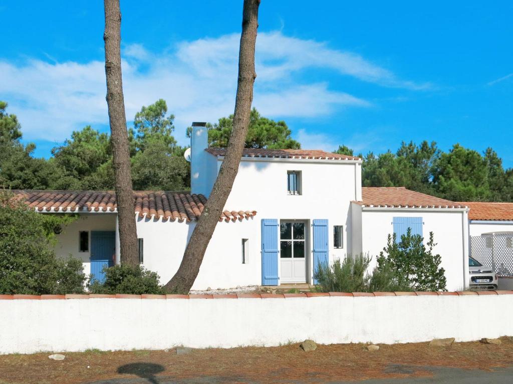 Maison blanche avec volets bleus et palmiers dans l'établissement Holiday Home Les Brisans by Interhome, à La Tranche-sur-Mer