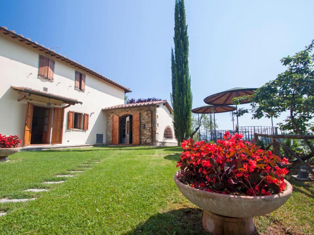 a house with a garden with red flowers in a yard at Apartment Lucia by Interhome in Podere Panzano