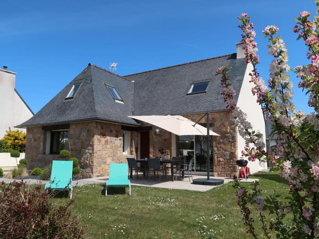 une maison avec une cour dotée de chaises et d'un parasol dans l'établissement Holiday Home Les Camélias - PGC106 by Interhome, à Perros-Guirec