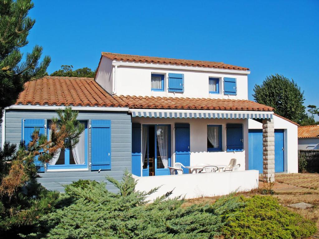 een wit huis met een rood dak en blauwe deuren bij Holiday Home Les Tourteaux - TSM200 by Interhome in La Tranche-sur-Mer