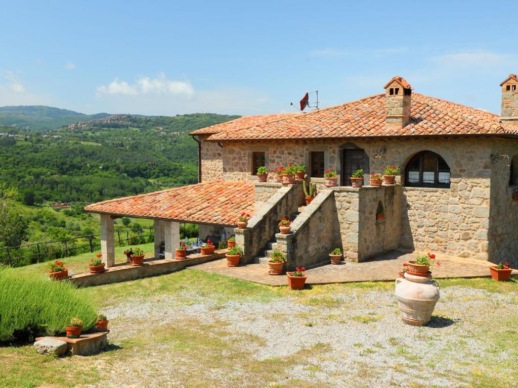 una casa in pietra con piante in vaso di fronte di Holiday Home Podere dei Venti by Interhome a Leccio