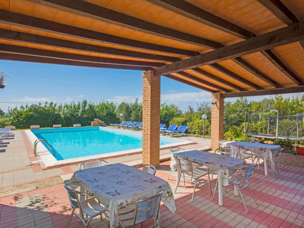 patio ze stołami i krzesłami oraz basenem w obiekcie Holiday Home Coast-2 by Interhome w mieście Bibbona
