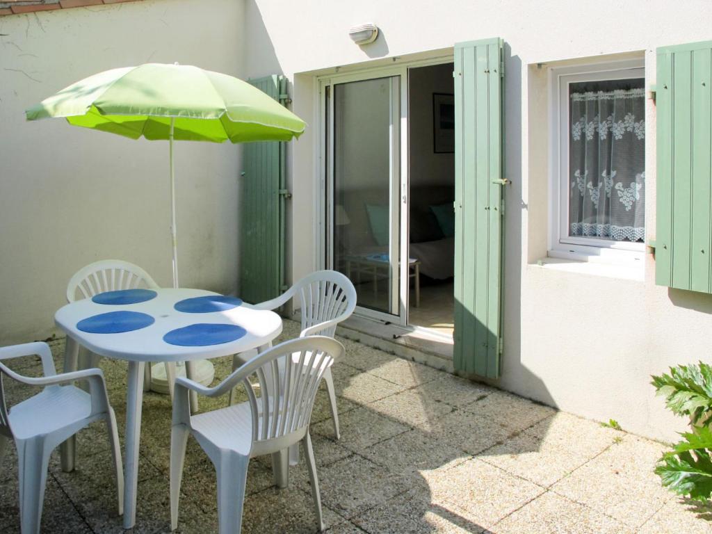 un patio avec une table, des chaises et un parasol dans l'établissement Holiday Home La Touche-2 by Interhome, à La Flotte
