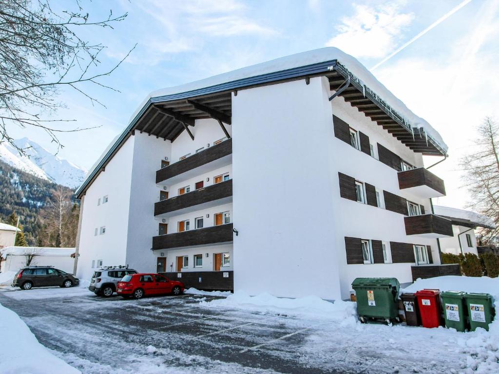 a building in the snow with trash cans in front of it at Apartment Am Birkenhain-28 by Interhome in Seefeld in Tirol