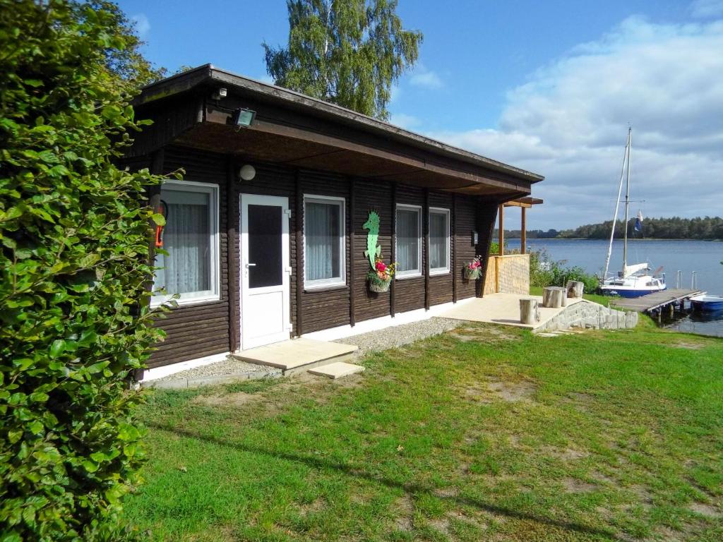 ein kleines Haus am Ufer eines Wasserkörpers in der Unterkunft Chalet Güstrower Chaussee by Interhome in Krakow am See