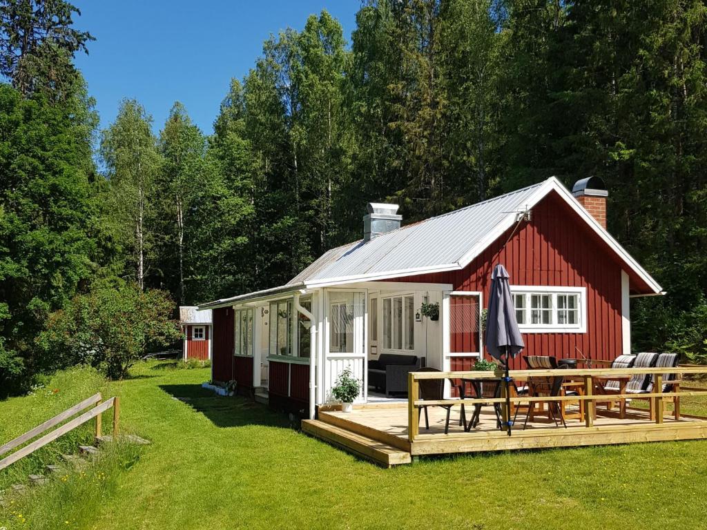 a red and white cabin with a wooden deck at Chalet Höje - VMD220 by Interhome in Hagfors