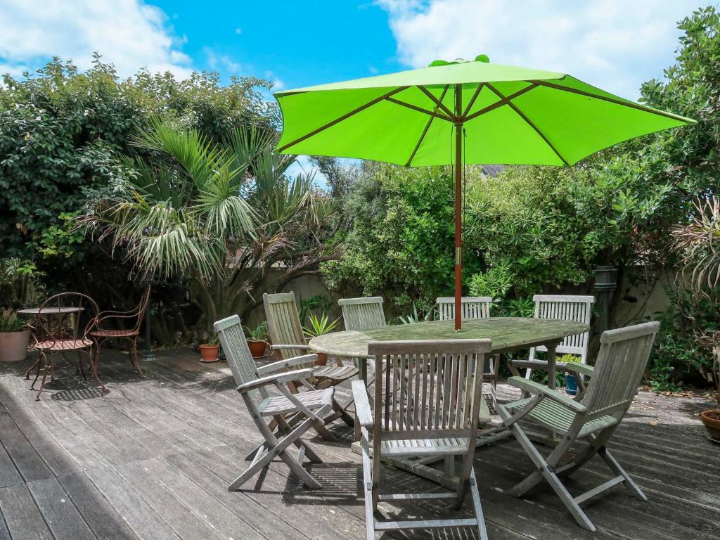 a table and chairs with a green umbrella at Holiday Home d'artistes by Interhome in Loctudy
