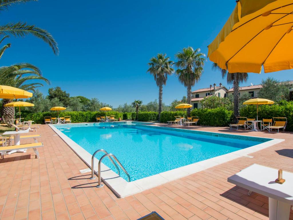 a swimming pool with tables and umbrellas at Apartment Le Macine-2 by Interhome in Cecina