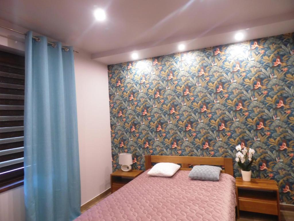 1 dormitorio con 1 cama y papel pintado con motivos florales en Zielone Zacisze, en Hajnówka