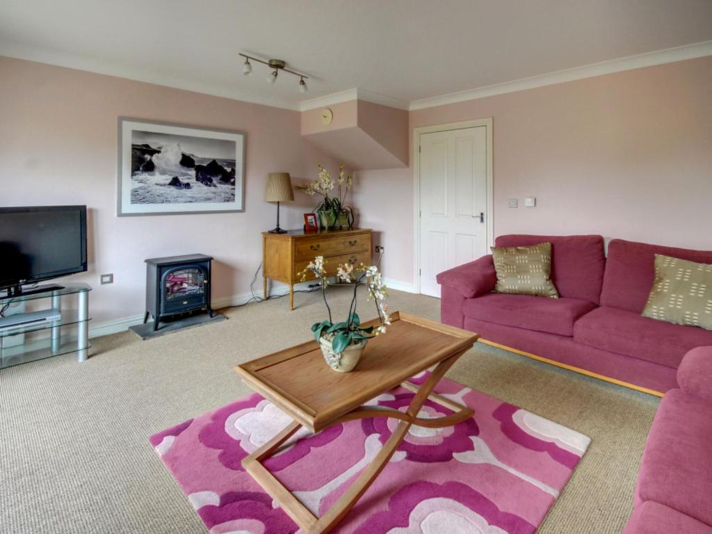 a living room with a purple couch and a fireplace at Holiday Home Valentines Cottage by Interhome in Braunton