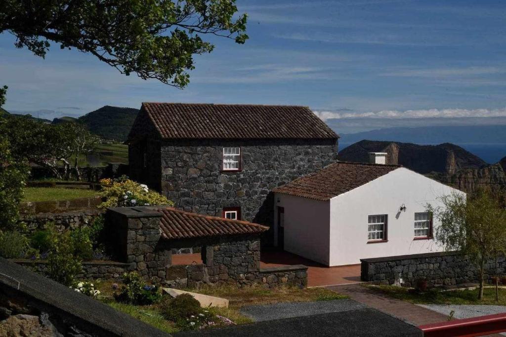 una pequeña casa de piedra con una casa blanca en Quinta das figueiras, en Velas