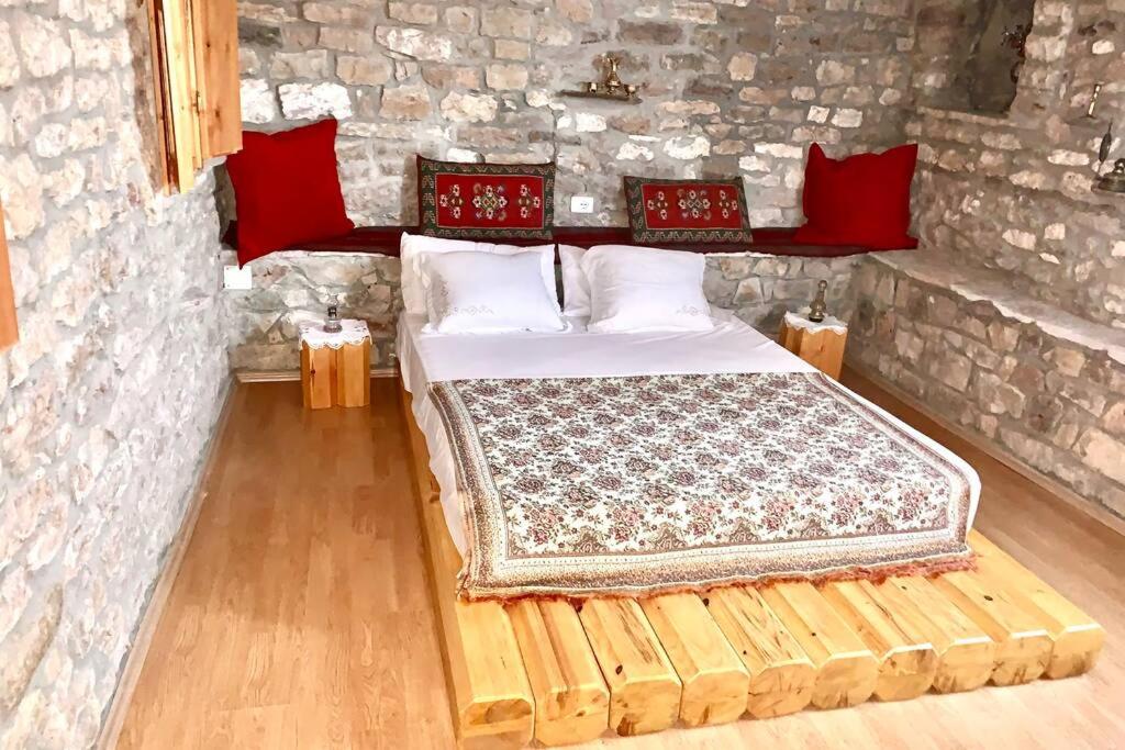 ein Schlafzimmer mit einem Bett in einer Steinmauer in der Unterkunft Kubeja Guest House in Gjirokastër